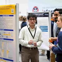 Three of our students in discussion around a research poster