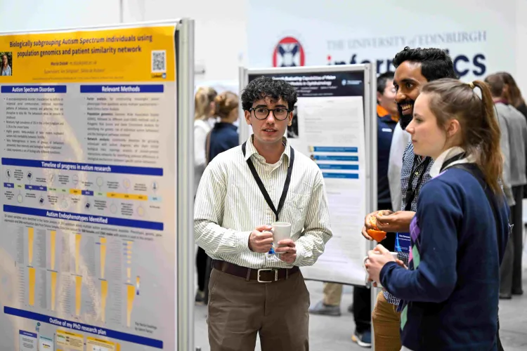 Three of our students in discussion around a research poster