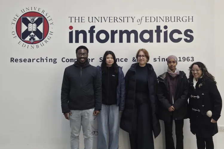 PhD researchers and their student shadows in front of the School of Informatics sign