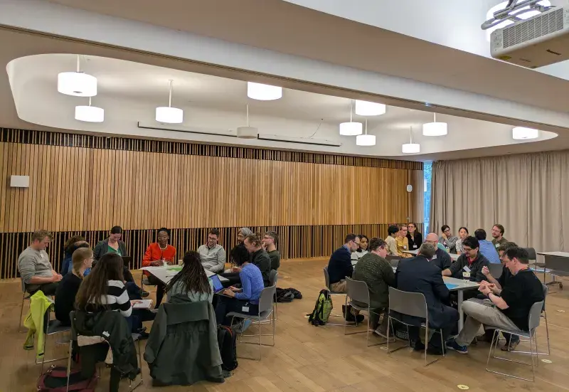 Groups of students and academics in discussion around tables